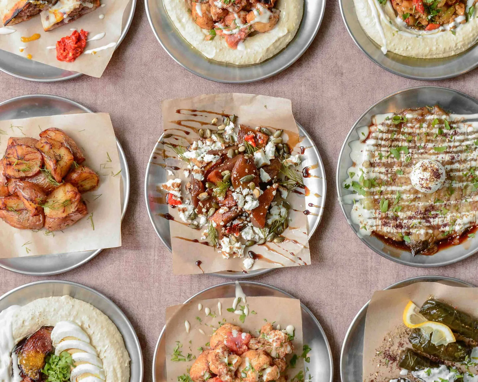 Mesa llena de platos de DosManos: hummus, pitas, falafel y entrantes